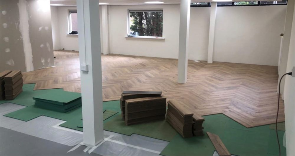 Laminaatplanken worden in stroken gelegd op een ondervloer