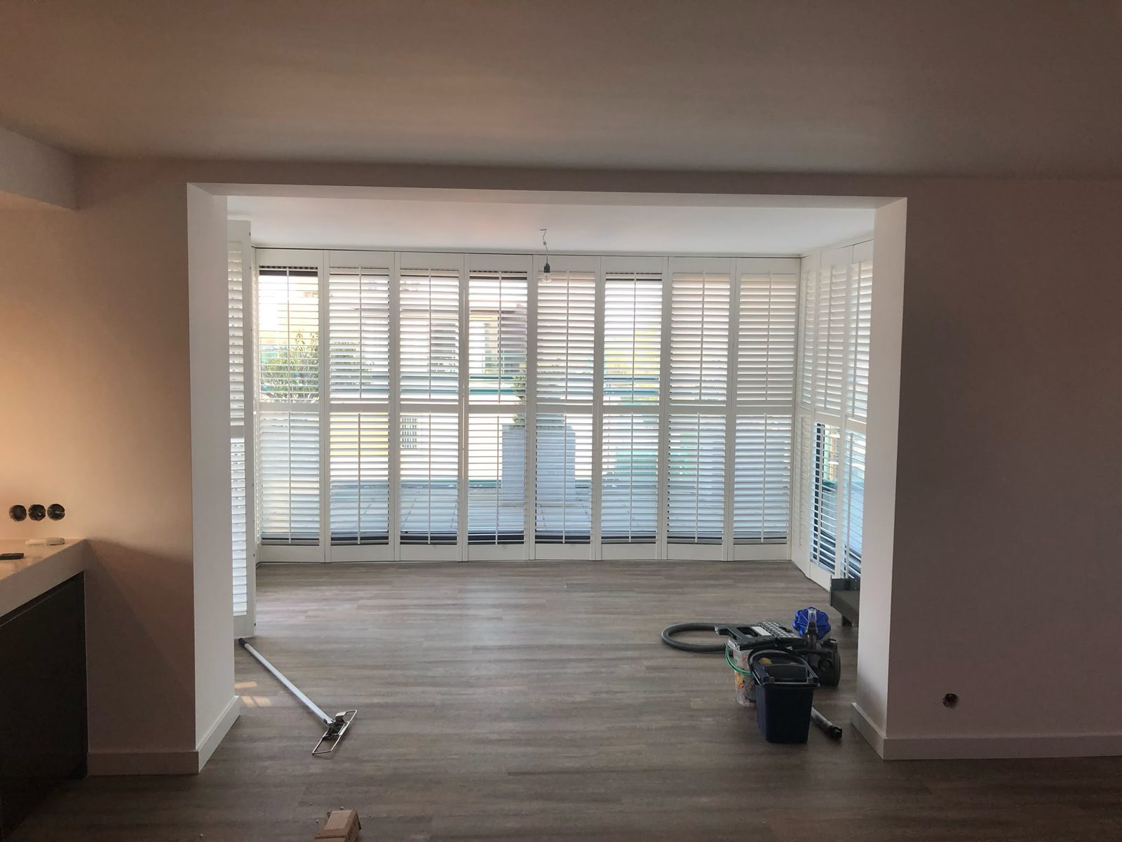Doorbraak vanuit de woonkamer naar de aanbouw, met shutters over de volle breedte
