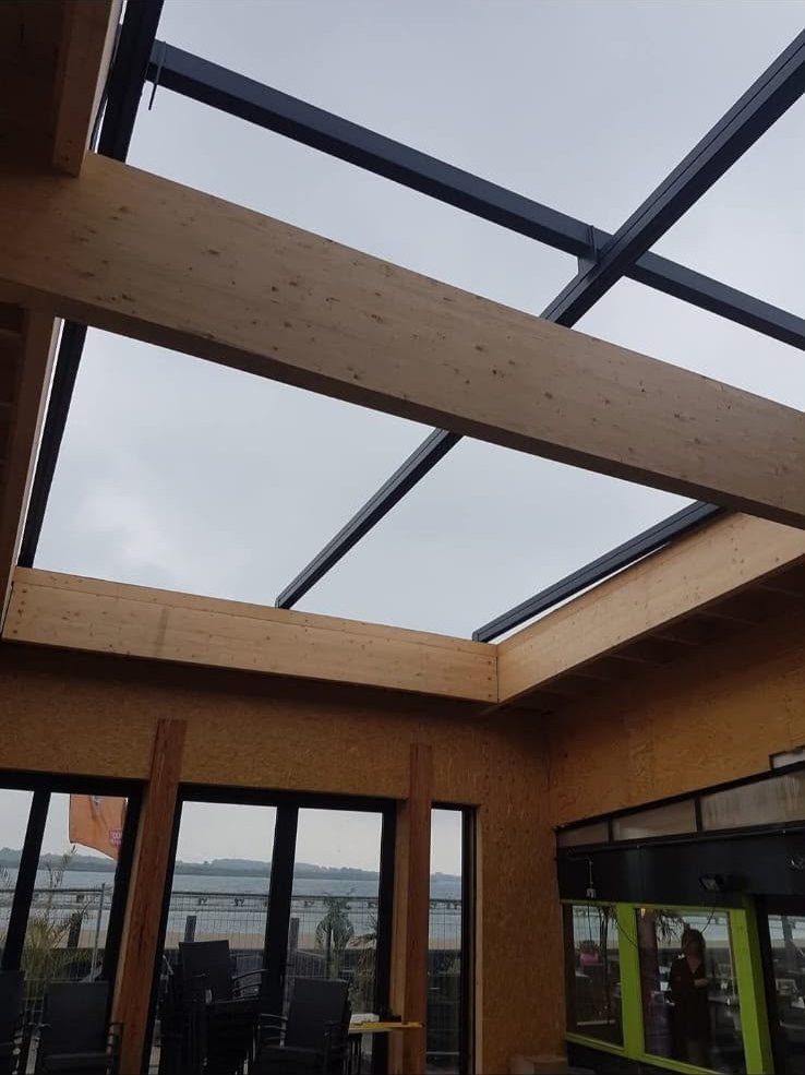 Lichtstraat in houtconstructie boven een terras met uitzicht over het water