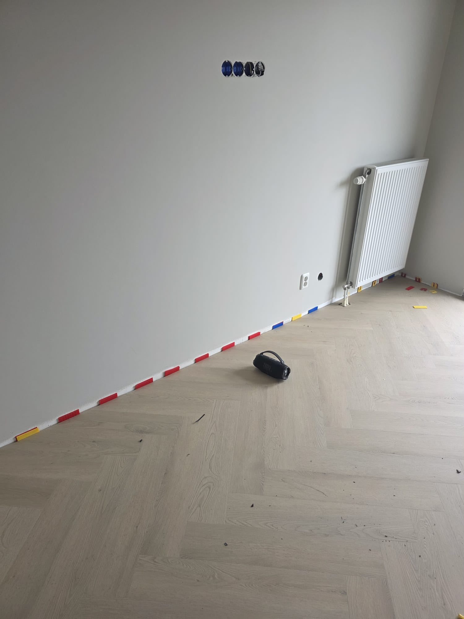 Stucwerk in Tiel: strak gestucte wand boven een nieuwe visgraatvloer bij oplevering