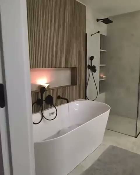 Badkamer met vrijstaand bad tegen een houten lamellenwand